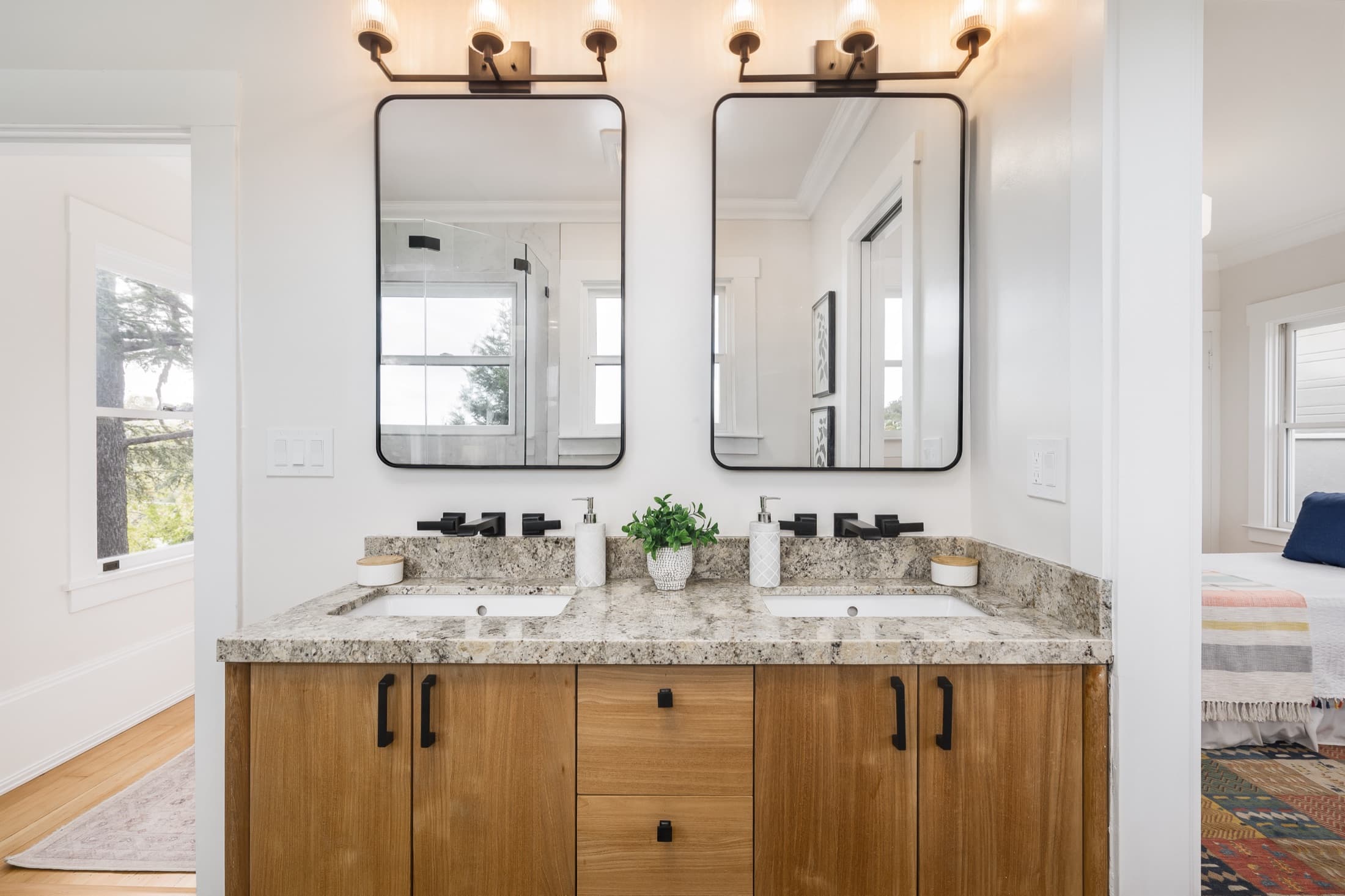 A double vanity in stone, wood, and blackened hardware.
